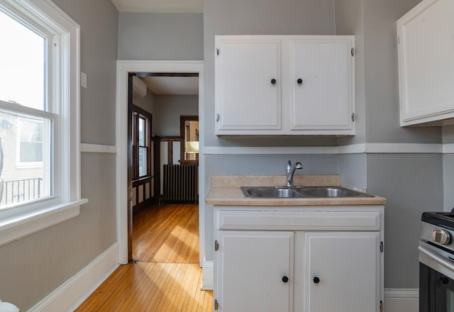 kitchen featuring stainless steel electric range oven, plenty of natural light, a sink, and radiator