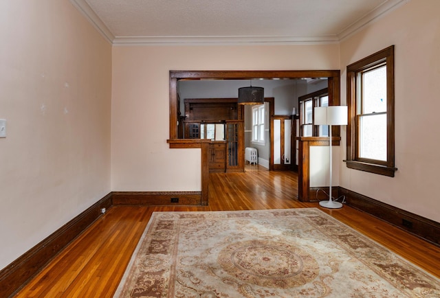 unfurnished room with crown molding, hardwood / wood-style floors, baseboards, and radiator