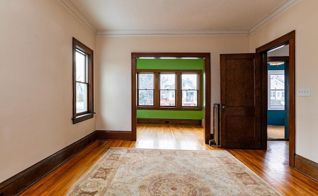 spare room with ornamental molding, baseboards, and wood finished floors