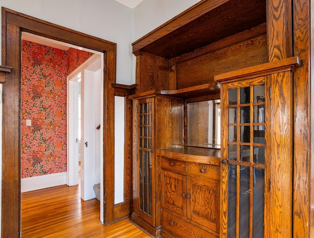 corridor with baseboards, light wood-style flooring, and wallpapered walls