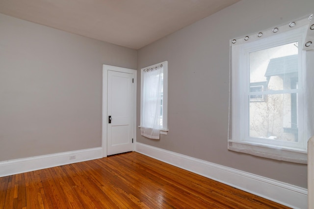 empty room with hardwood / wood-style floors, baseboards, and a wealth of natural light