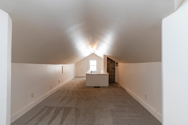 additional living space featuring light carpet, baseboards, and vaulted ceiling