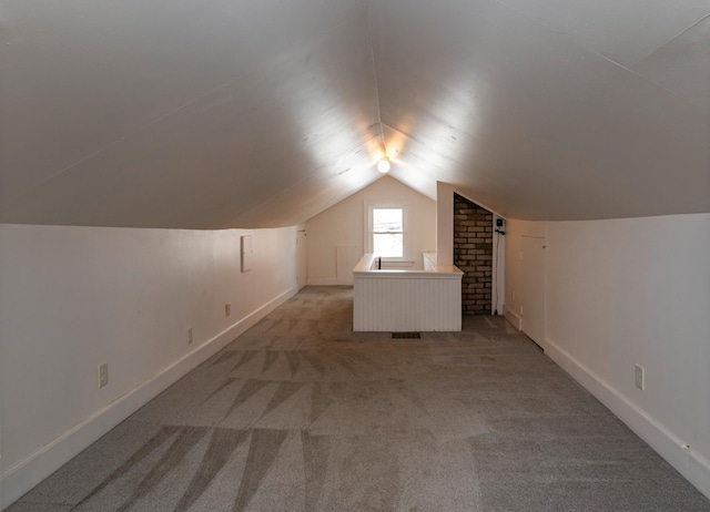 bonus room with vaulted ceiling, light carpet, and baseboards