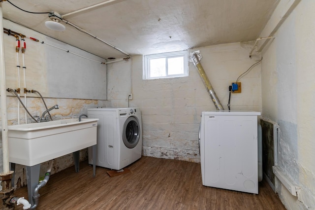 laundry area with concrete block wall, laundry area, wood finished floors, and washing machine and clothes dryer