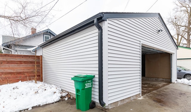 view of side of home with a garage, an outbuilding, and fence