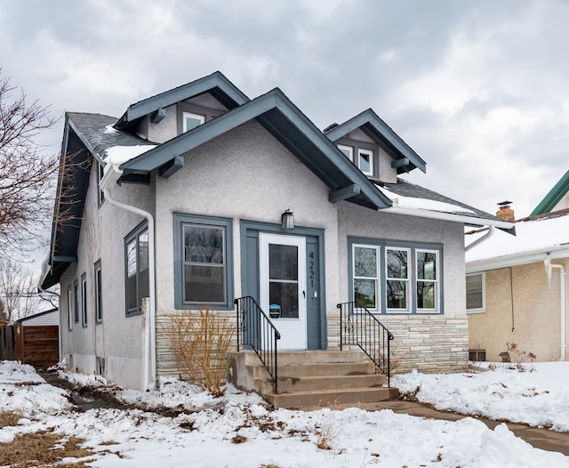 bungalow-style house with stone siding and stucco siding