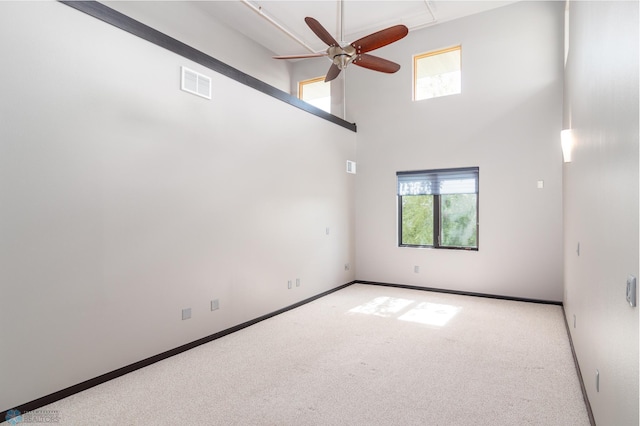 carpeted spare room with a high ceiling and ceiling fan