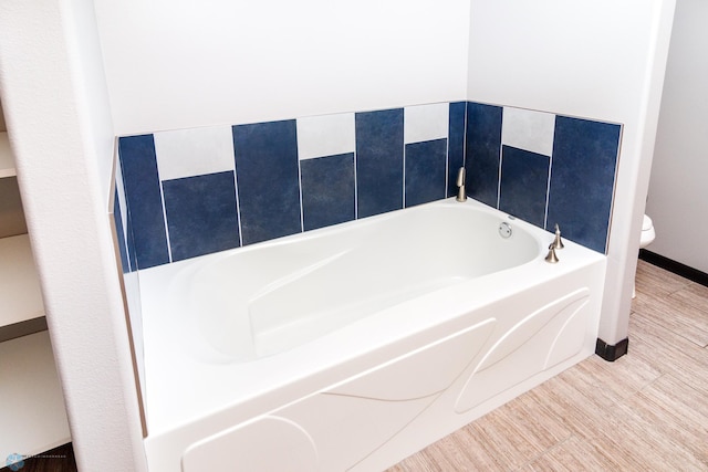 bathroom featuring wood-type flooring, a washtub, and toilet