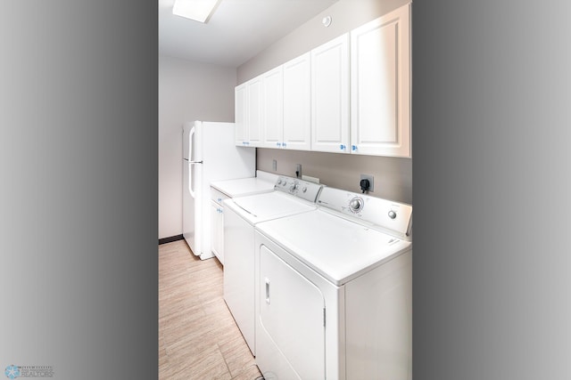 washroom with cabinets, washing machine and dryer, and light wood-type flooring