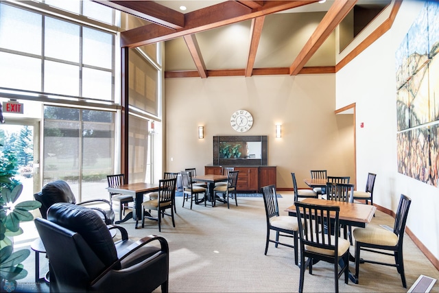 carpeted dining room with a high ceiling and beam ceiling