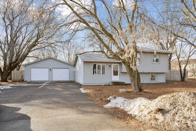 tri-level home with an outbuilding, entry steps, a detached garage, and fence