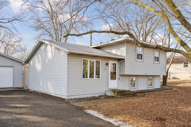 split level home featuring a garage, driveway, and an outdoor structure