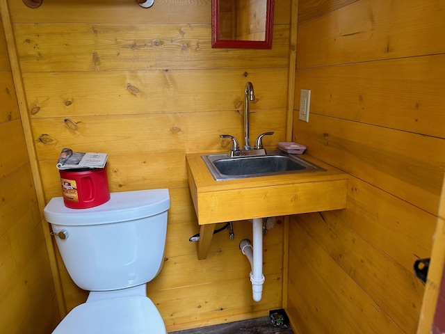 bathroom featuring sink, toilet, and wood walls