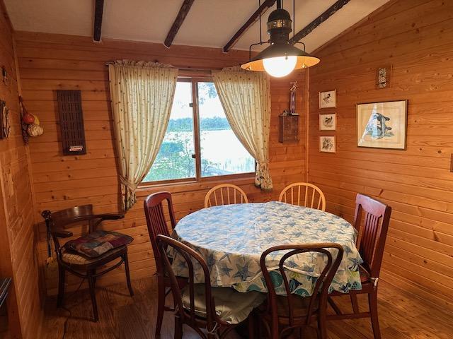 dining area featuring vaulted ceiling with beams, wood-type flooring, and wood walls