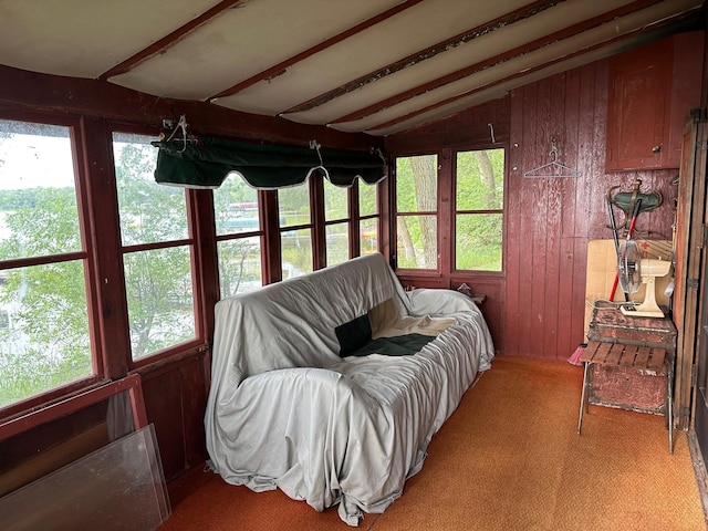 carpeted living room with vaulted ceiling and wood walls