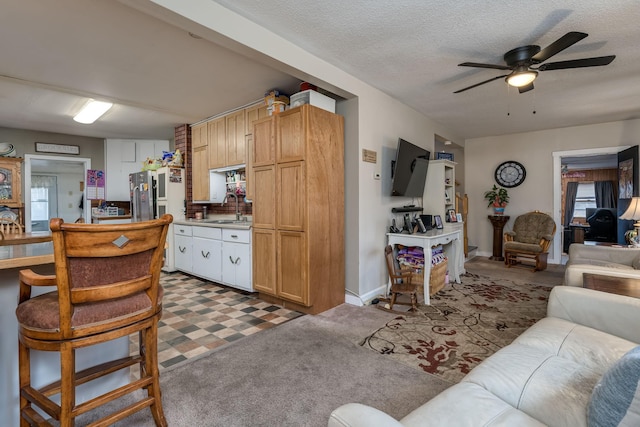 living room featuring ceiling fan, sink, and a textured ceiling