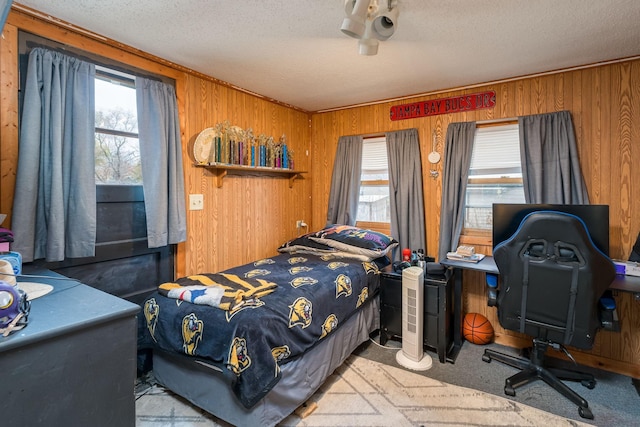 bedroom featuring light colored carpet, a textured ceiling, and wood walls