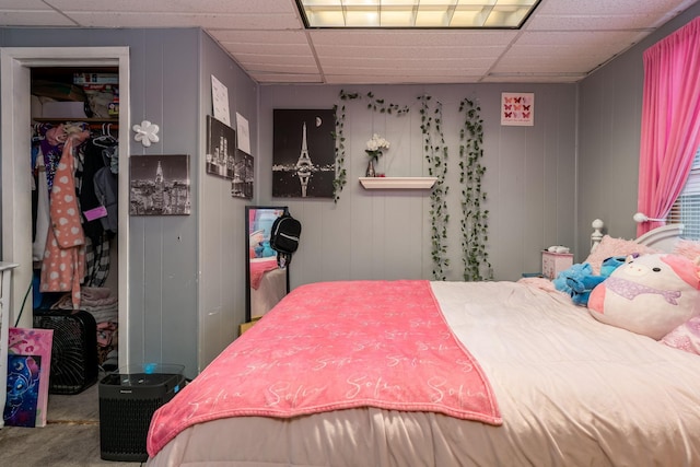 carpeted bedroom with a paneled ceiling, a closet, and a walk in closet