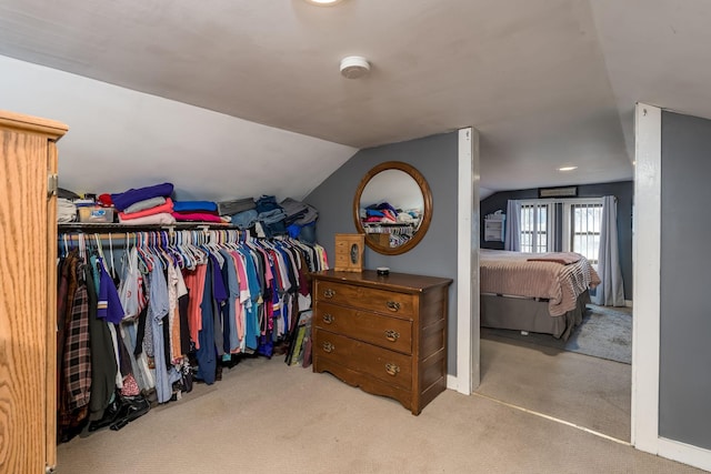 walk in closet with lofted ceiling and light colored carpet