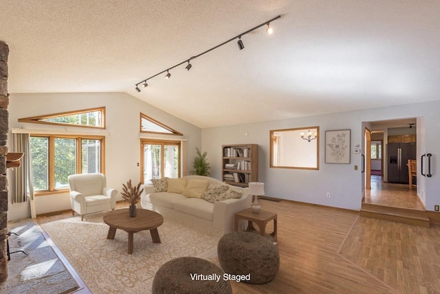 living room featuring vaulted ceiling, a textured ceiling, and light wood-type flooring