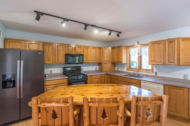 kitchen featuring butcher block counters, sink, a center island, light hardwood / wood-style floors, and black appliances