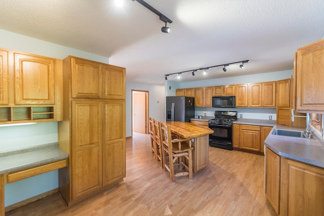 kitchen featuring a textured ceiling, sink, light hardwood / wood-style flooring, and black appliances