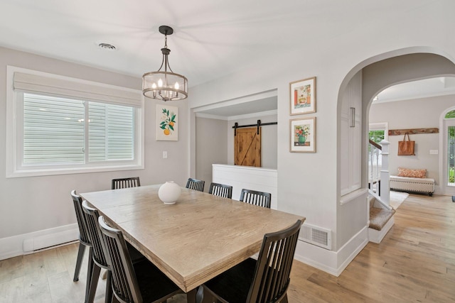 1989 Iglehart Ave, Saint Paul, MN 55104 - dining area featuring a barn door, light wood-type flooring, a chandelier, baseboards, and arched walkways