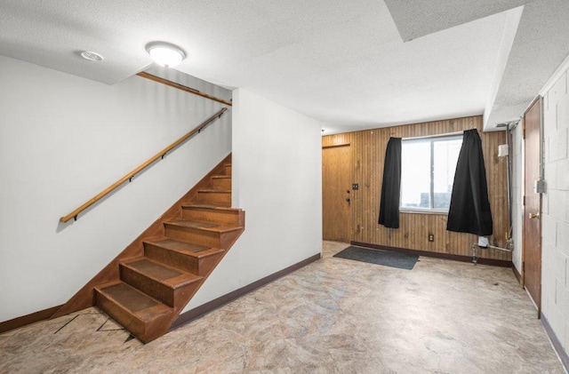 entryway featuring a textured ceiling and wood walls