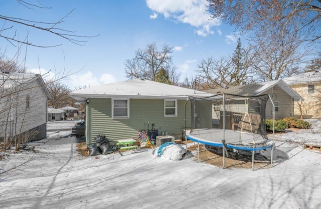 snow covered property with central AC and a trampoline