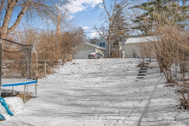 yard covered in snow featuring a garage and a trampoline