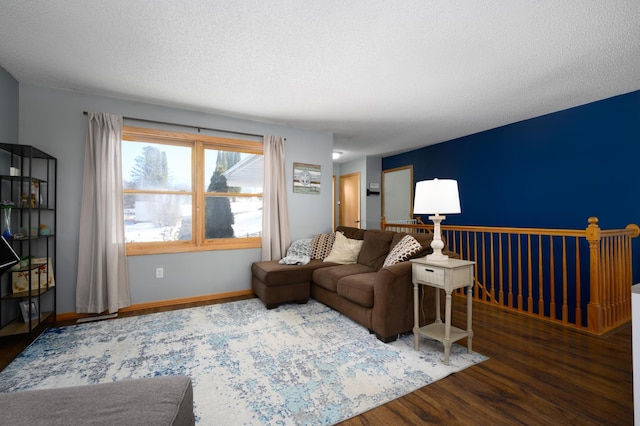 living room featuring a textured ceiling, baseboards, and wood finished floors