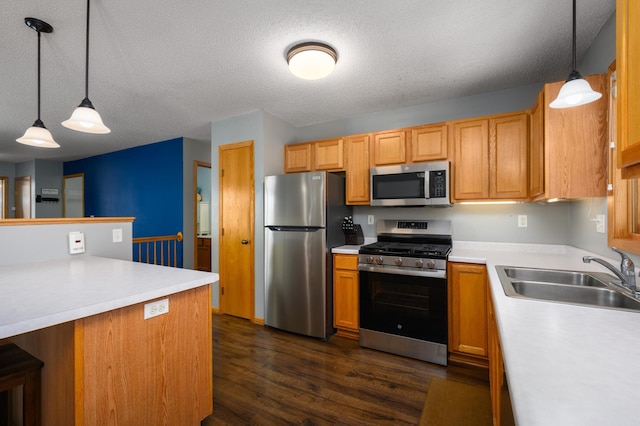 kitchen featuring dark wood finished floors, light countertops, appliances with stainless steel finishes, and a sink