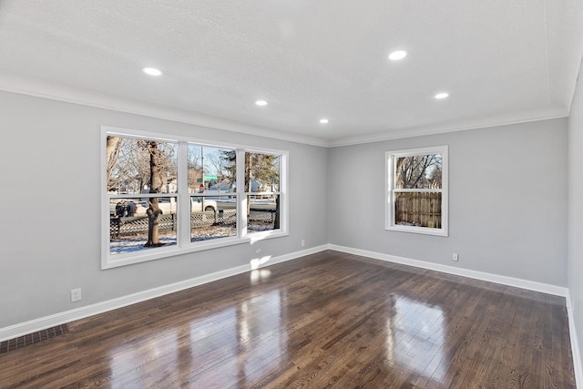 empty room with dark wood-type flooring, plenty of natural light, and ornamental molding