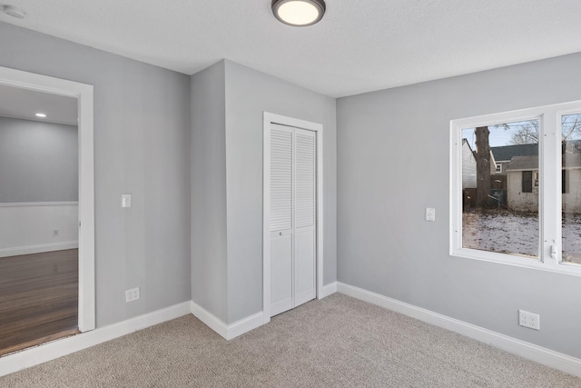 unfurnished bedroom featuring a closet, a textured ceiling, and carpet