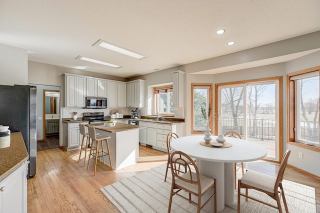 dining area featuring sink, a textured ceiling, and light wood-type flooring