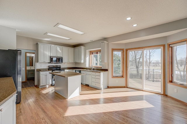 kitchen with stainless steel appliances, plenty of natural light, sink, and light hardwood / wood-style flooring