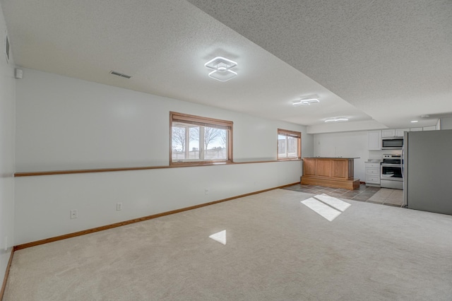 unfurnished living room with light carpet and a textured ceiling