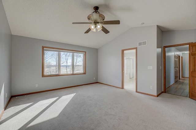 empty room with ceiling fan, lofted ceiling, light colored carpet, and a textured ceiling