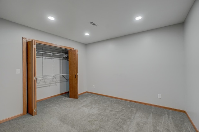 unfurnished bedroom with light colored carpet and a closet