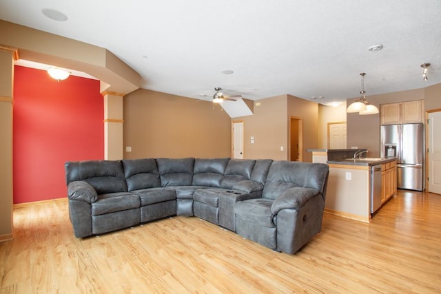 living room featuring ceiling fan, lofted ceiling, sink, and light hardwood / wood-style flooring