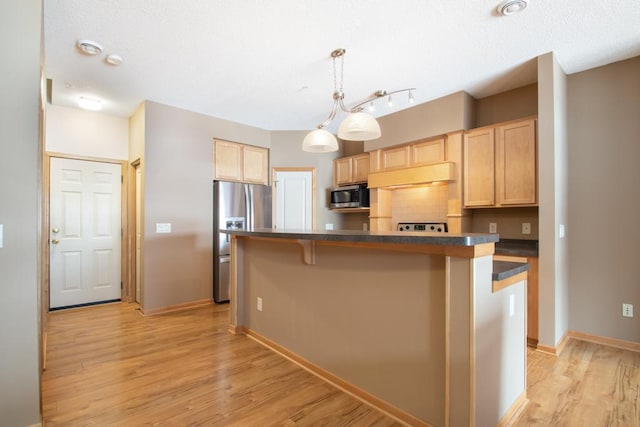 kitchen with hanging light fixtures, light brown cabinets, a center island, and appliances with stainless steel finishes