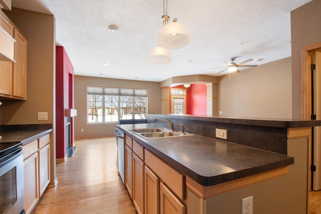 kitchen with an island with sink, stove, sink, and pendant lighting