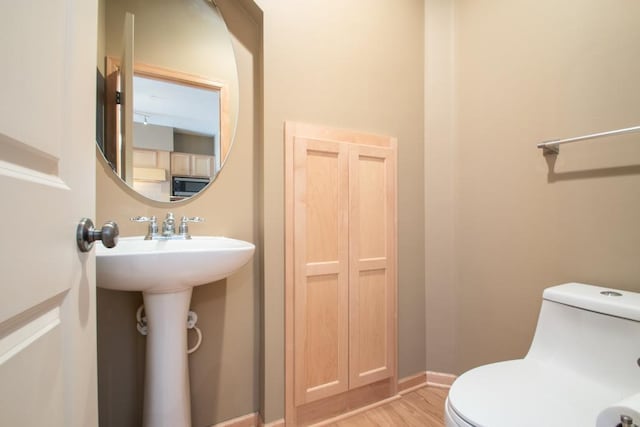 bathroom featuring wood-type flooring and toilet