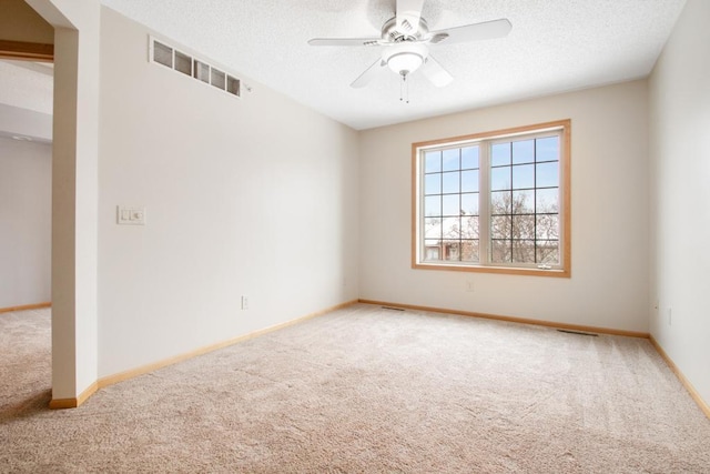 carpeted empty room featuring ceiling fan and a textured ceiling