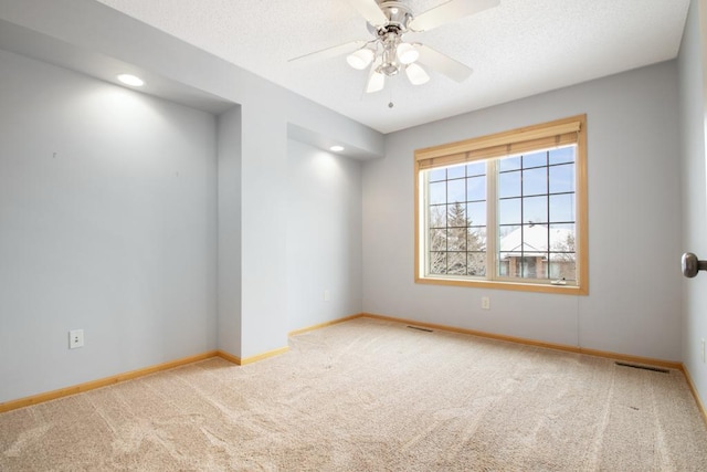 spare room with ceiling fan, light carpet, and a textured ceiling