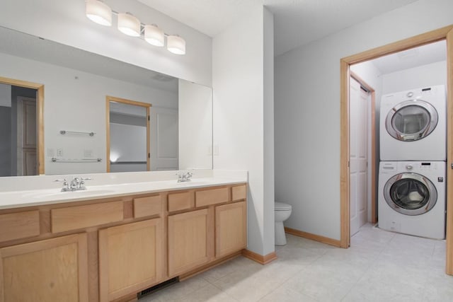 bathroom featuring vanity, stacked washer / drying machine, tile patterned floors, and toilet