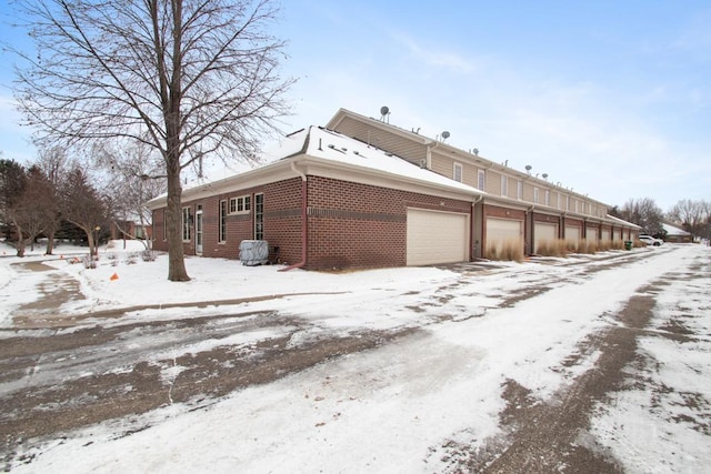 view of snow covered exterior featuring a garage