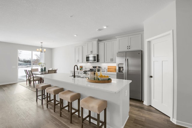 kitchen featuring appliances with stainless steel finishes, a breakfast bar area, a center island with sink, and sink