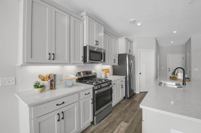 kitchen with sink, appliances with stainless steel finishes, tasteful backsplash, white cabinets, and dark hardwood / wood-style flooring