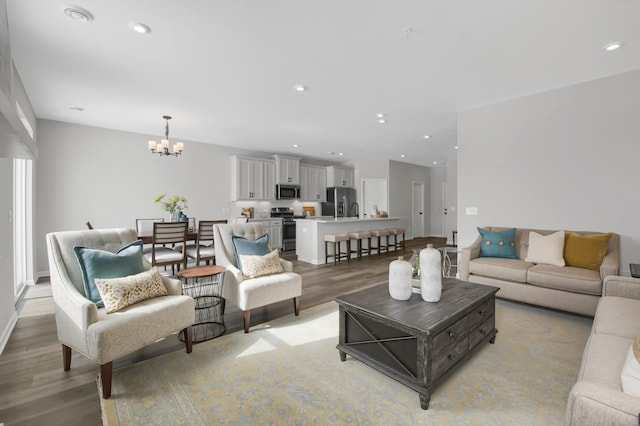 living room with sink, a notable chandelier, and light hardwood / wood-style floors